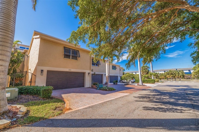 view of front of house featuring decorative driveway, an attached garage, and stucco siding