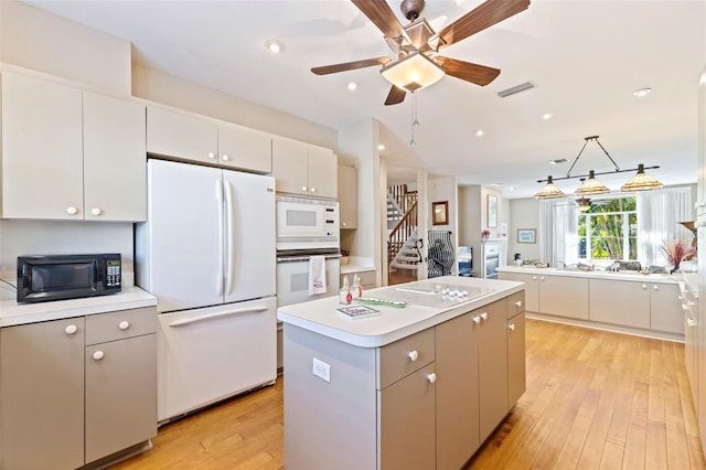 kitchen featuring white appliances, light hardwood / wood-style flooring, hanging light fixtures, a center island, and white cabinets