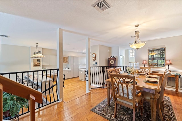 dining area featuring a textured ceiling and light hardwood / wood-style flooring