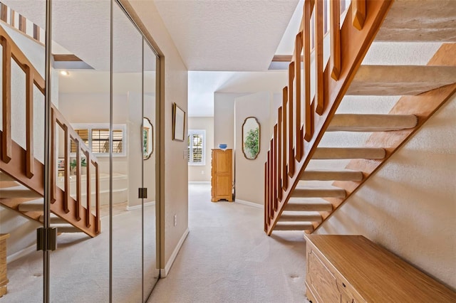 hall with light carpet and a textured ceiling