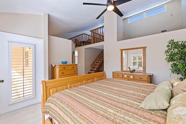 bedroom featuring multiple windows, ceiling fan, and a high ceiling