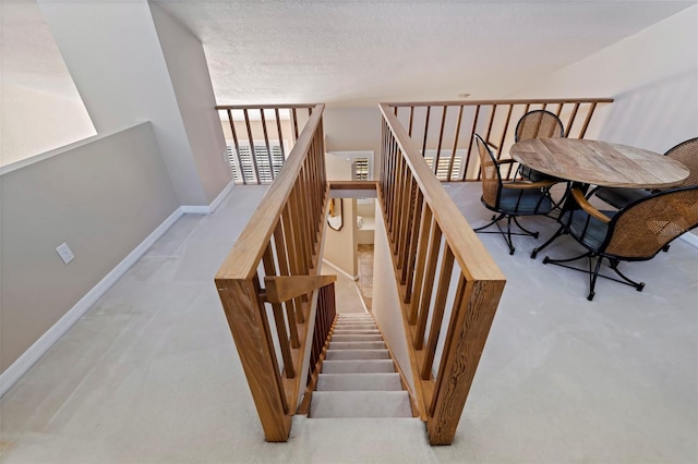 stairway featuring a textured ceiling and carpet flooring