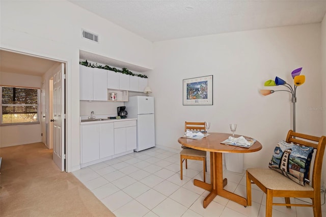 kitchen with sink, white cabinetry, light carpet, a textured ceiling, and white fridge