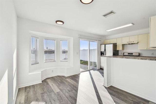 kitchen featuring stainless steel refrigerator with ice dispenser, cream cabinets, range, and light hardwood / wood-style floors