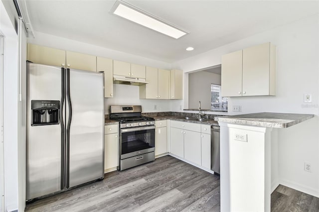 kitchen featuring sink, hardwood / wood-style floors, stainless steel appliances, cream cabinets, and kitchen peninsula