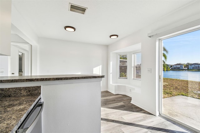 kitchen featuring a water view, stainless steel dishwasher, and light hardwood / wood-style flooring