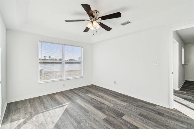 unfurnished room with ceiling fan, a tray ceiling, and dark hardwood / wood-style floors