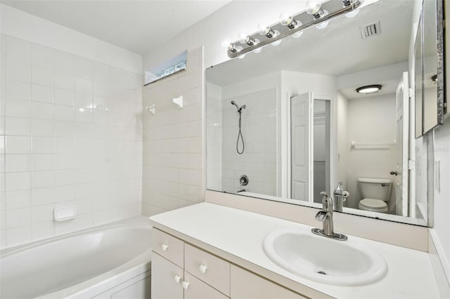 full bathroom with tiled shower / bath, vanity, and toilet