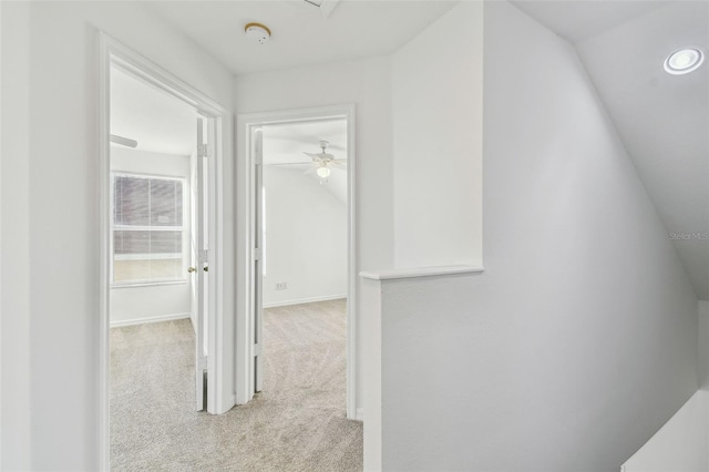 hallway with vaulted ceiling and light carpet