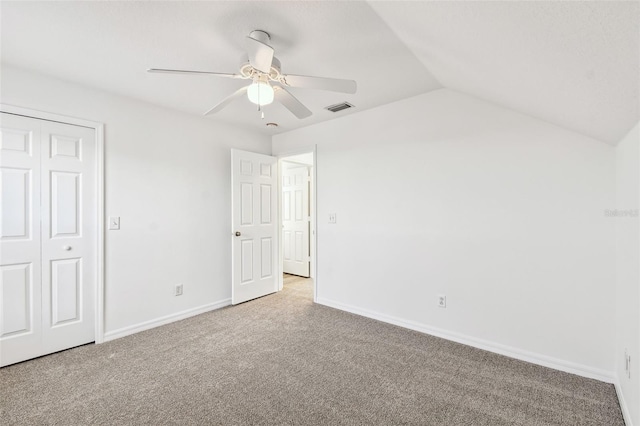 unfurnished bedroom with light carpet, vaulted ceiling, a closet, and ceiling fan