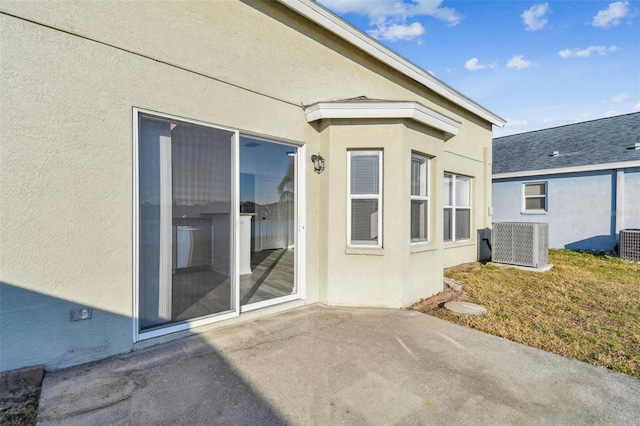 view of exterior entry with central AC unit and a patio area