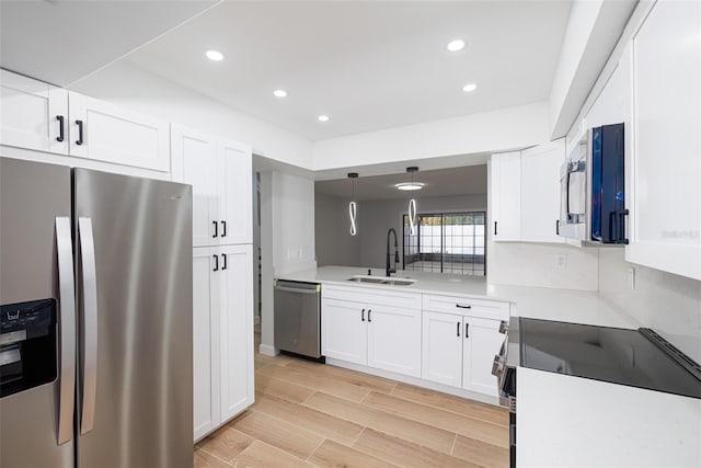 kitchen with white cabinetry, sink, hanging light fixtures, and appliances with stainless steel finishes