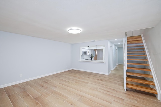 basement featuring sink and light hardwood / wood-style floors