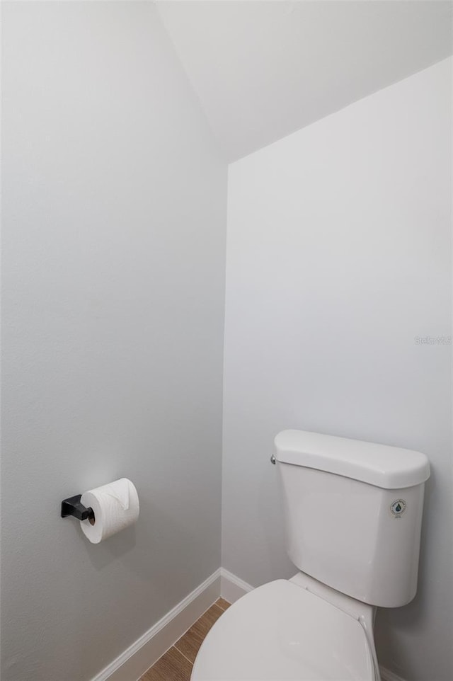 bathroom with hardwood / wood-style flooring, vaulted ceiling, and toilet