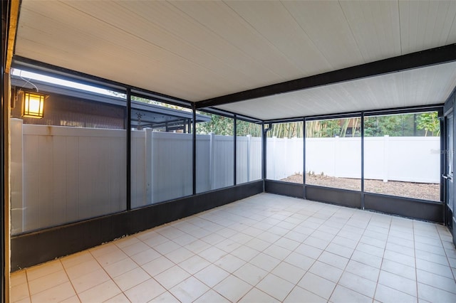 unfurnished sunroom featuring beamed ceiling