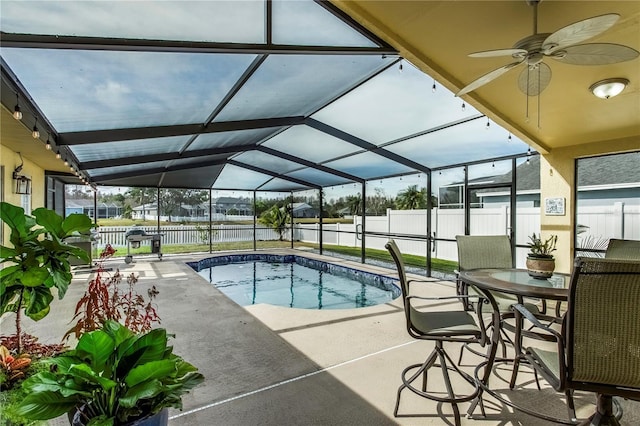 view of swimming pool with ceiling fan, a patio, and glass enclosure