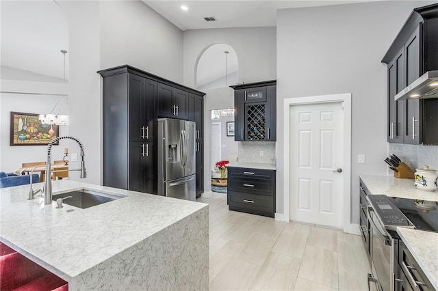 kitchen featuring appliances with stainless steel finishes, a breakfast bar, sink, decorative backsplash, and a center island with sink