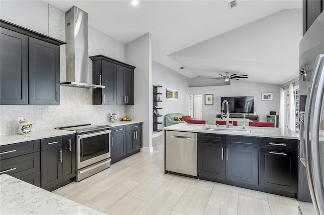 kitchen featuring lofted ceiling, sink, ceiling fan, stainless steel appliances, and wall chimney range hood