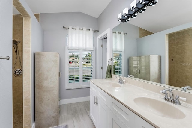 bathroom featuring a tile shower, vanity, and vaulted ceiling