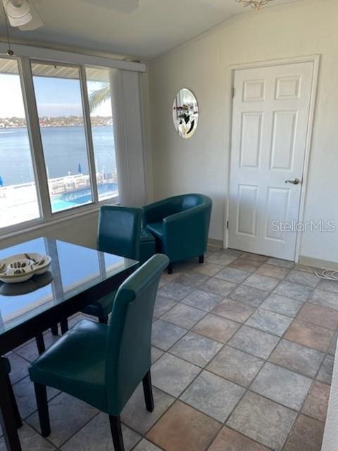 dining room featuring vaulted ceiling, ceiling fan, and a water view