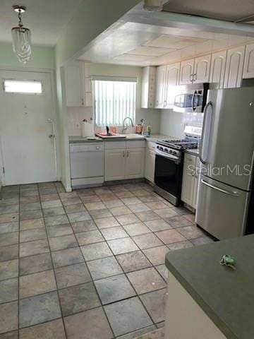 kitchen featuring pendant lighting, appliances with stainless steel finishes, sink, and white cabinets