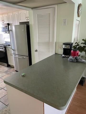 kitchen featuring appliances with stainless steel finishes, kitchen peninsula, light hardwood / wood-style flooring, and white cabinets