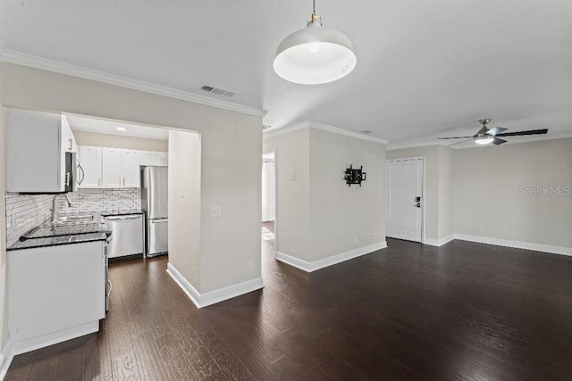 kitchen with appliances with stainless steel finishes, sink, white cabinets, backsplash, and dark wood-type flooring