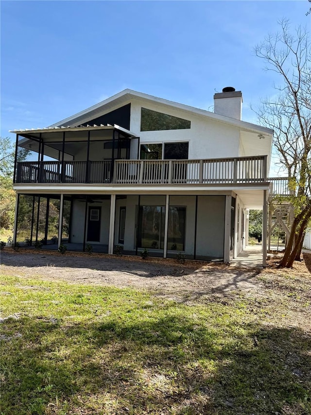 rear view of house featuring a wooden deck and a lawn