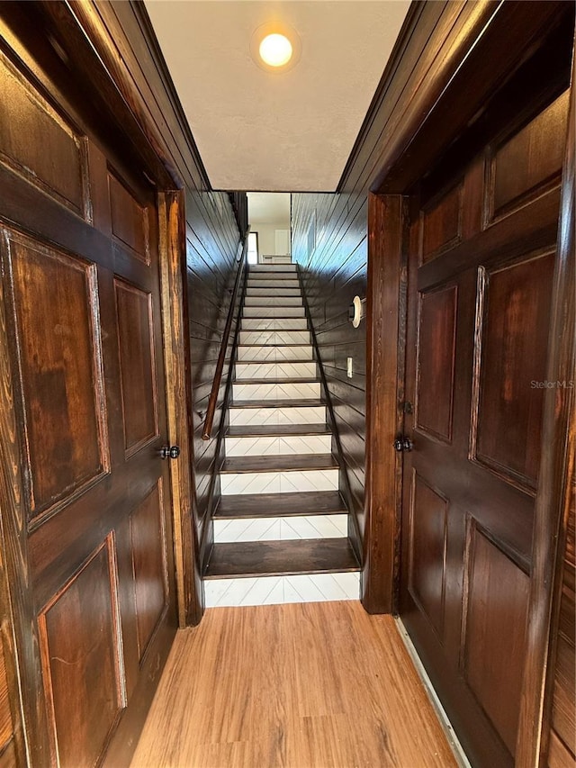 stairs with hardwood / wood-style flooring and wood walls