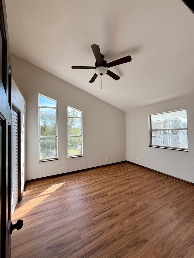 empty room with lofted ceiling, hardwood / wood-style floors, and ceiling fan