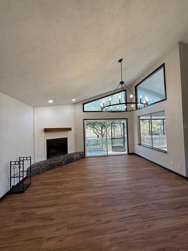 unfurnished living room with lofted ceiling, dark wood-type flooring, a chandelier, and a textured ceiling