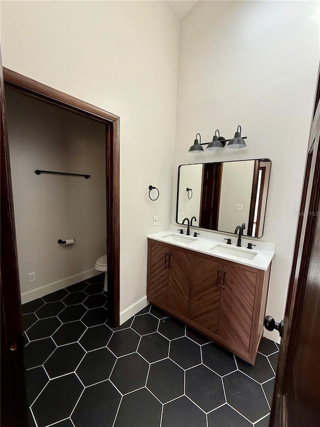 bathroom featuring vanity, a towering ceiling, tile patterned floors, and toilet