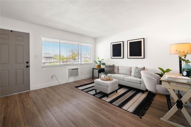 living room with wood-type flooring, a wall mounted AC, and a textured ceiling