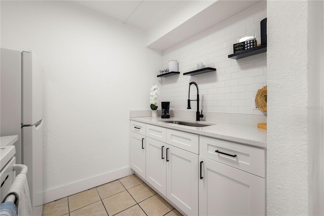 kitchen featuring light tile patterned flooring, sink, white cabinets, backsplash, and white refrigerator