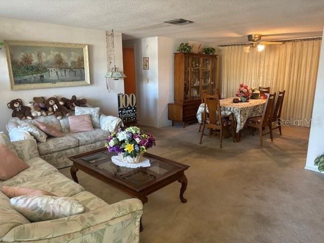 carpeted living room featuring ceiling fan and a textured ceiling