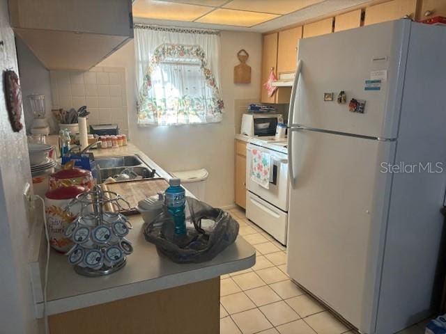 kitchen featuring white appliances, light brown cabinets, and light tile patterned flooring