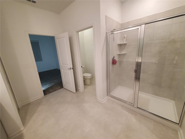 bathroom featuring a shower with shower door and toilet