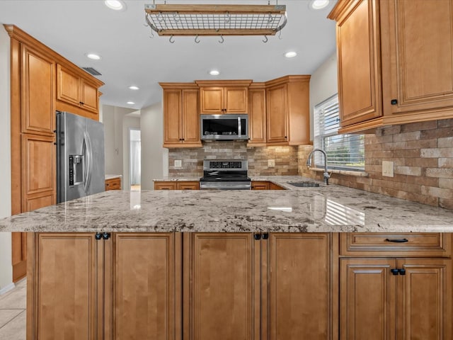 kitchen with light stone counters, stainless steel appliances, sink, and tasteful backsplash