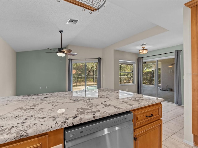 kitchen featuring a healthy amount of sunlight, vaulted ceiling, dishwasher, and light tile patterned flooring