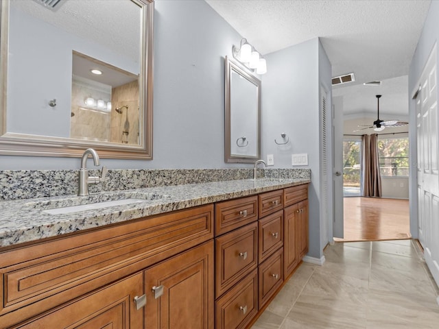 bathroom with vanity, a tile shower, tile patterned floors, and a textured ceiling