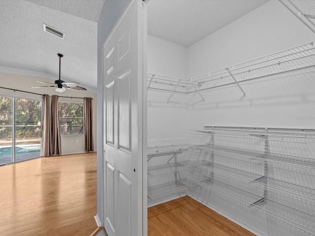 spacious closet with vaulted ceiling, light hardwood / wood-style floors, and ceiling fan