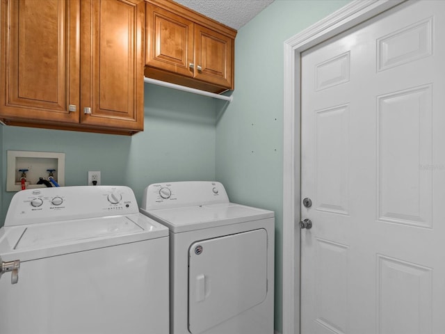 washroom with washing machine and dryer, cabinets, and a textured ceiling