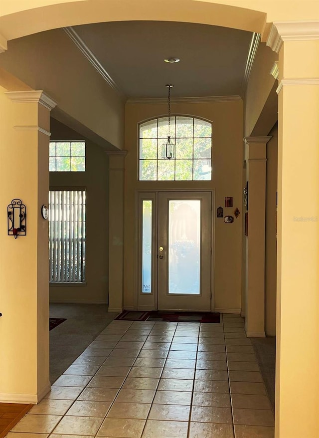 foyer with crown molding, tile patterned floors, and ornate columns