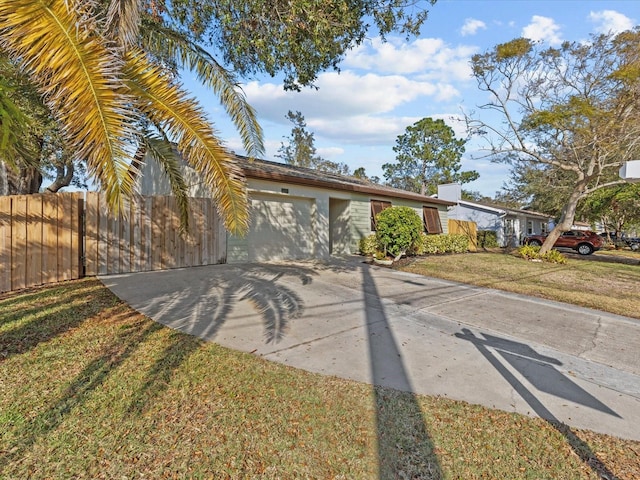 view of front of home with a front yard, fence, an attached garage, stucco siding, and concrete driveway