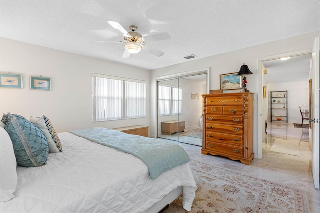 bedroom with ceiling fan, a textured ceiling, and a closet