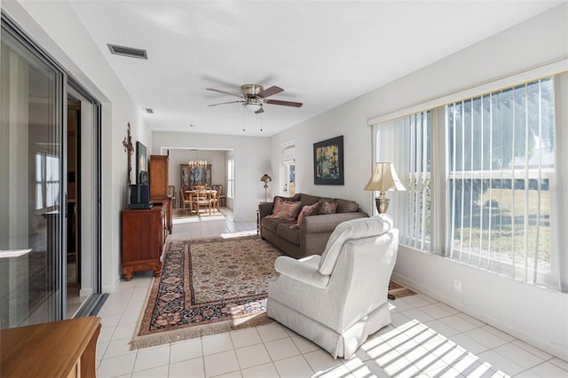 living room with ceiling fan with notable chandelier, a textured ceiling, and light tile patterned floors