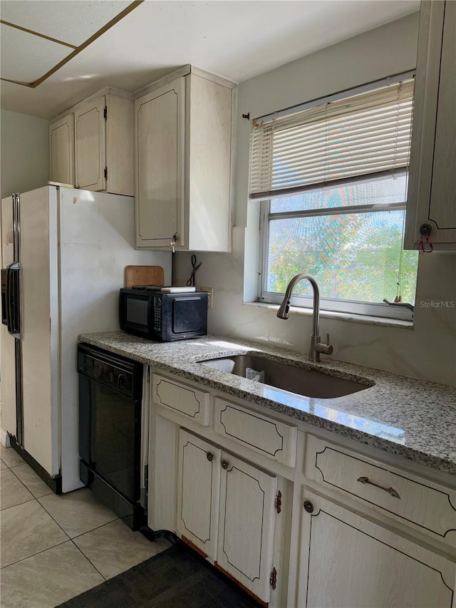 kitchen with light stone counters, light tile patterned floors, sink, and black appliances