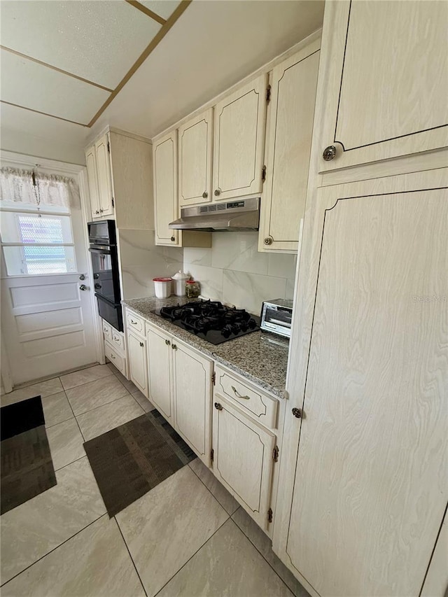 kitchen featuring light stone countertops, light tile patterned floors, decorative backsplash, and black appliances