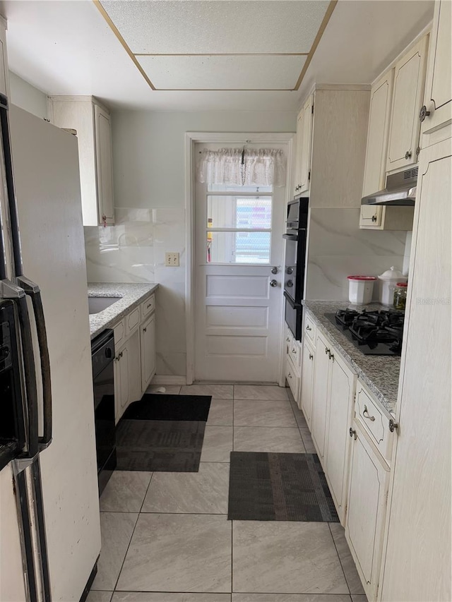 kitchen with light stone counters and black appliances