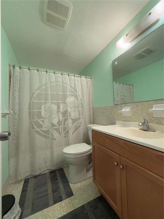 bathroom with lofted ceiling, tile patterned flooring, tile walls, vanity, and toilet